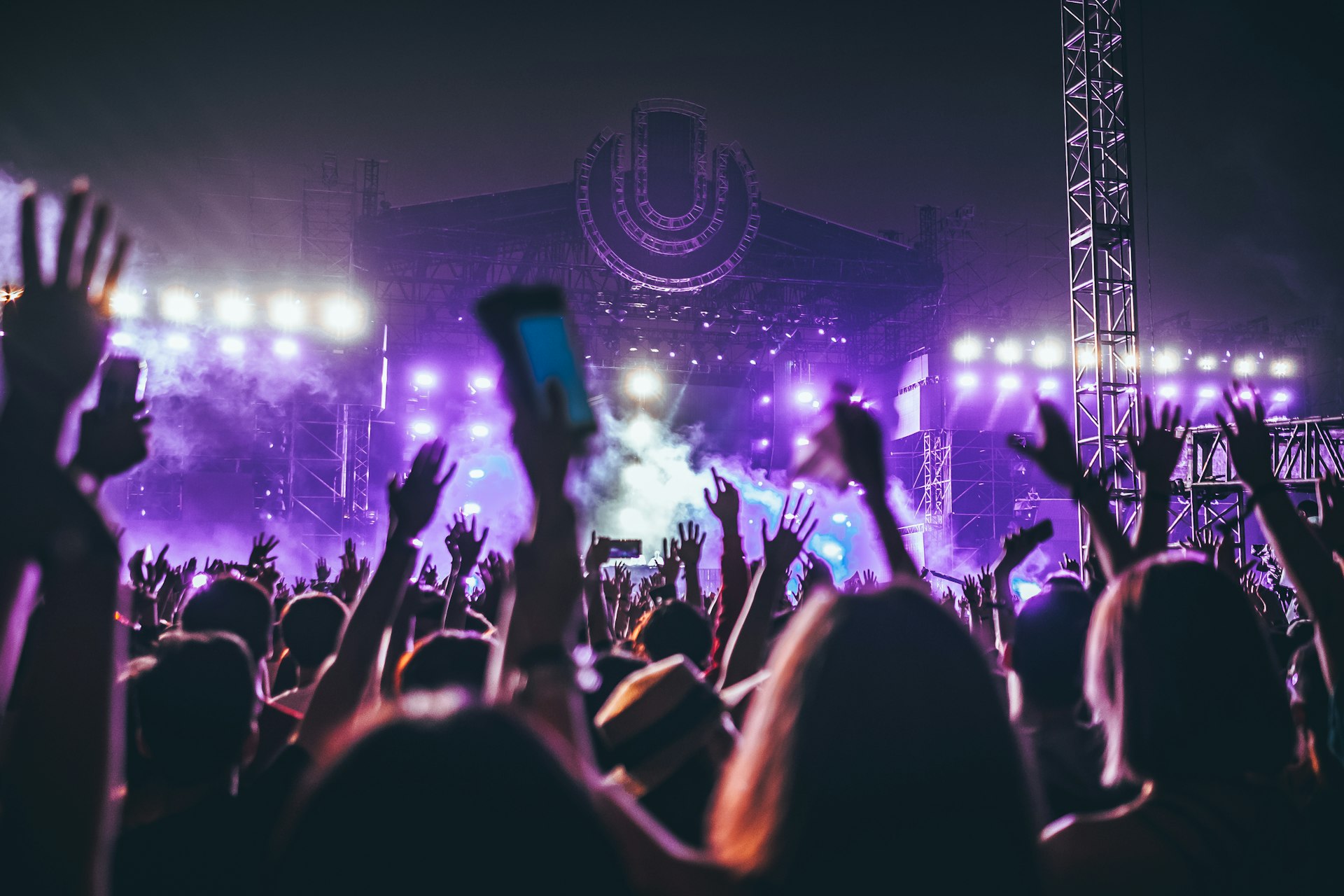 Festival crowd with raised hands before a lit main stage