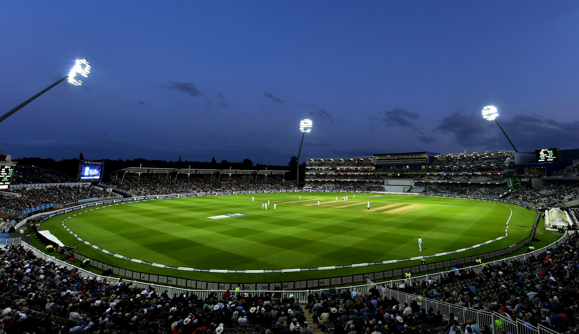 Floodlit stadium at dusk with full stands