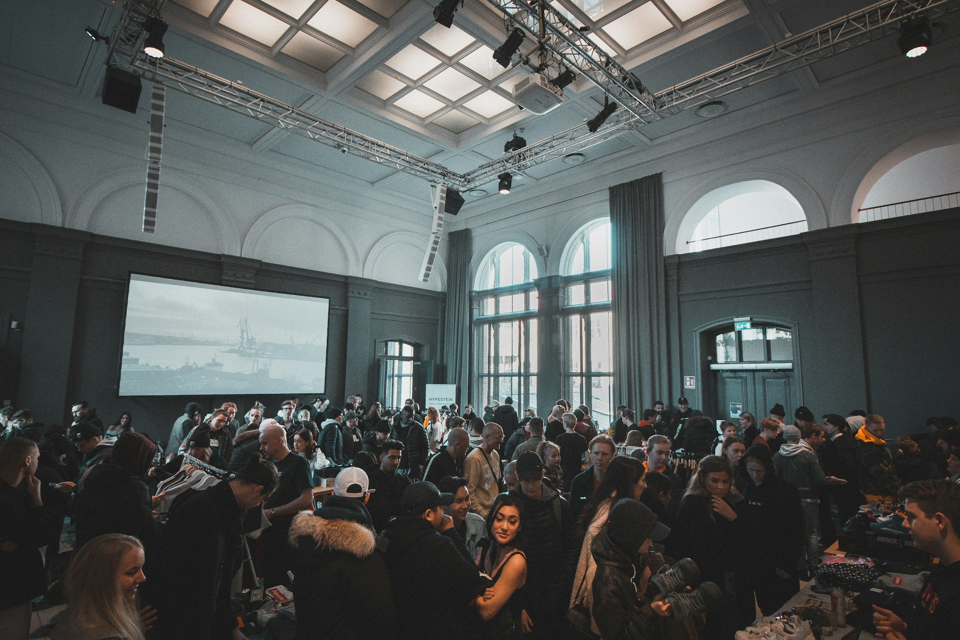 Packed indoor event space with overhead lighting truss